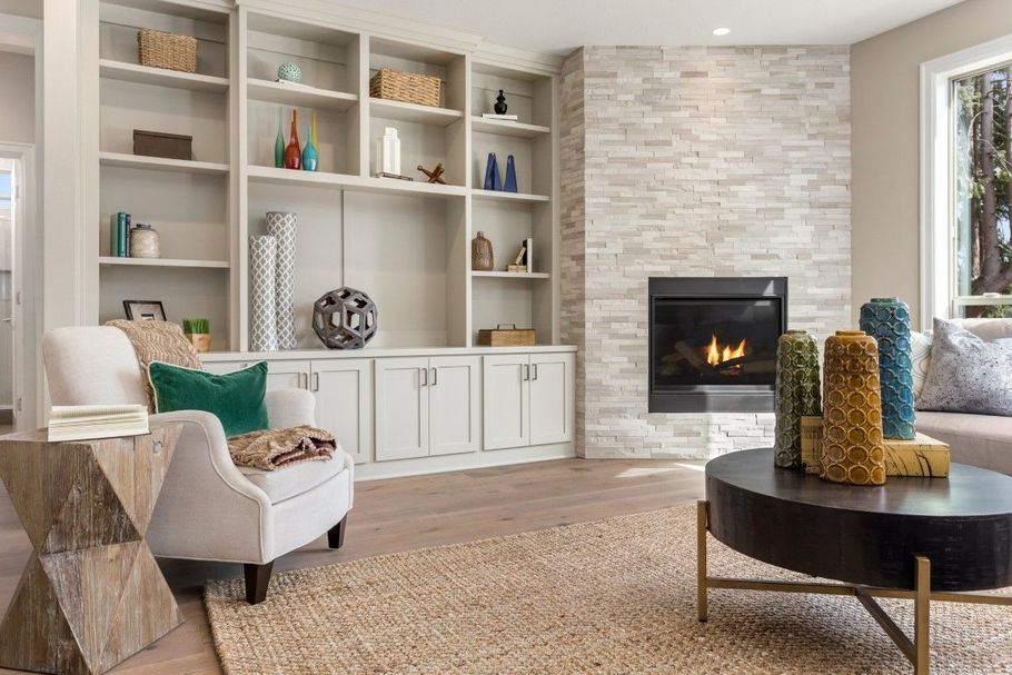 Cozy living room with built-in shelves, fireplace, armchair, and round coffee table in neutral tones