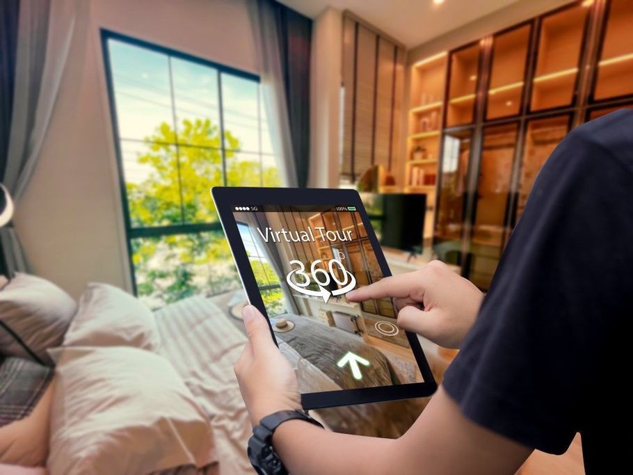 Person holding a tablet in a modern bedroom with a digital home control interface on screen