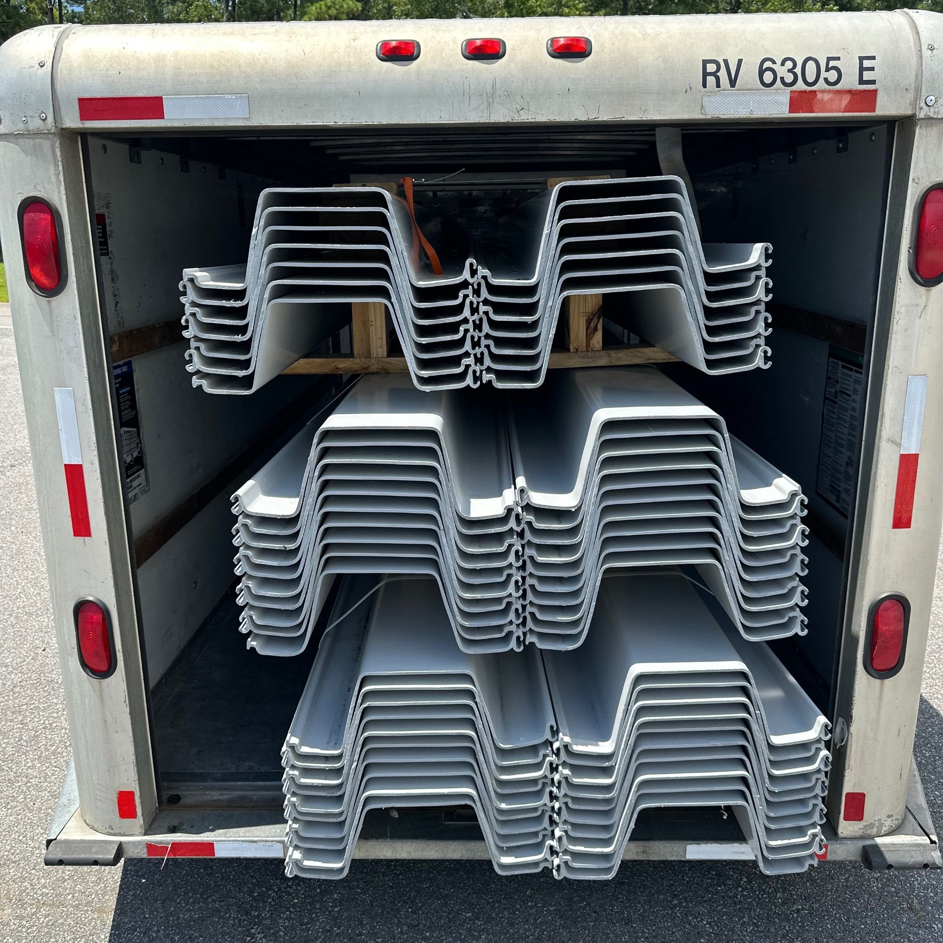 Trailer loaded with stacks of folded metal chairs inside an open rear door.