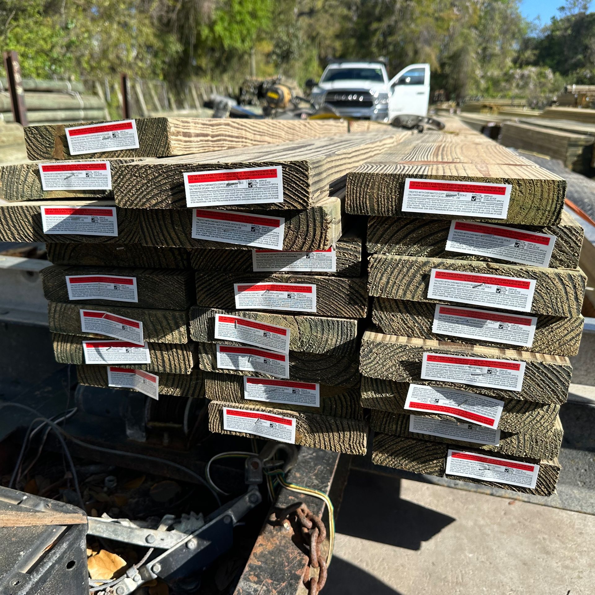 Stacked pallets of tan landscaping blocks with red-and-white labels on a flatbed truck outdoors.