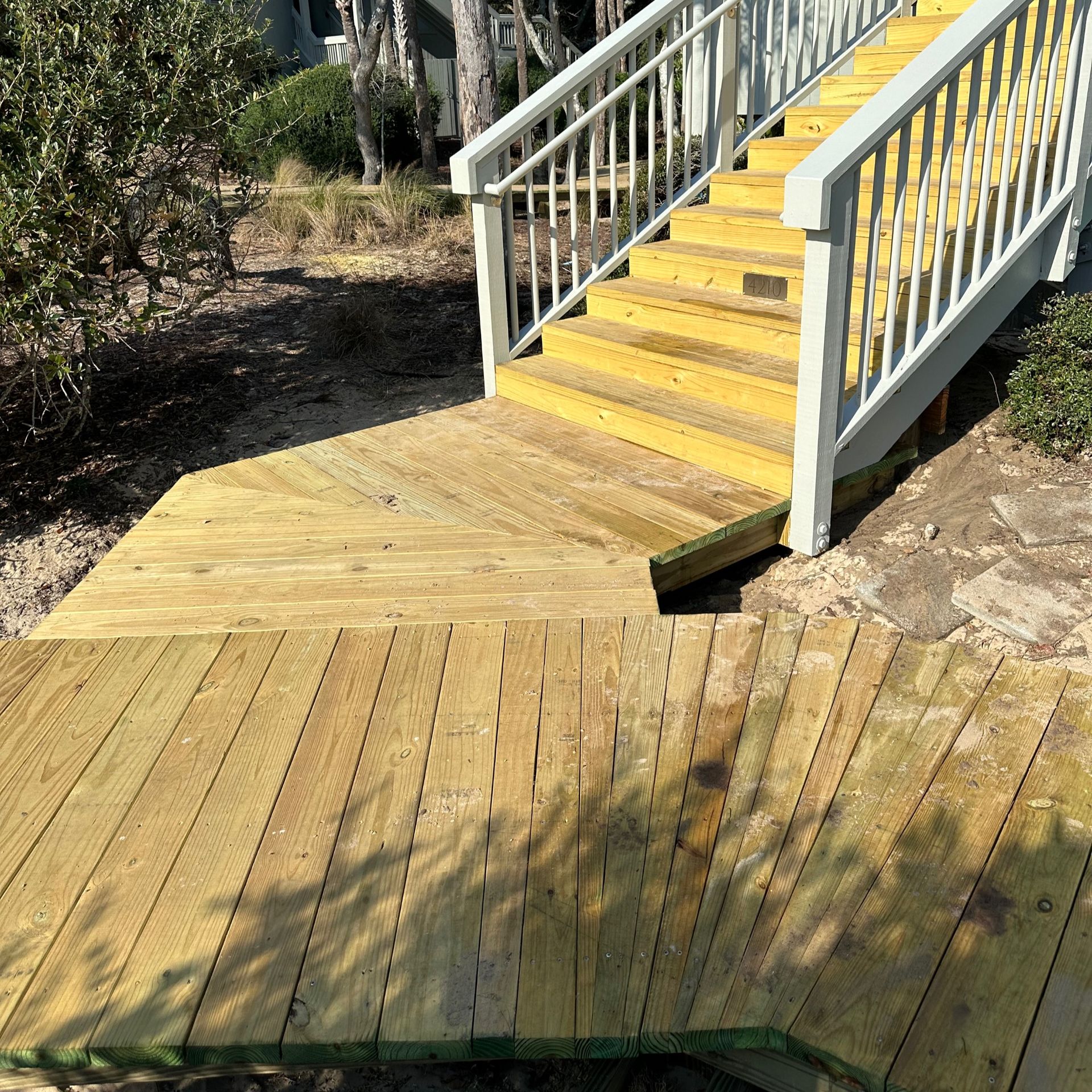 Wooden accessible ramp and stairs with yellow steps and white railings outdoors.