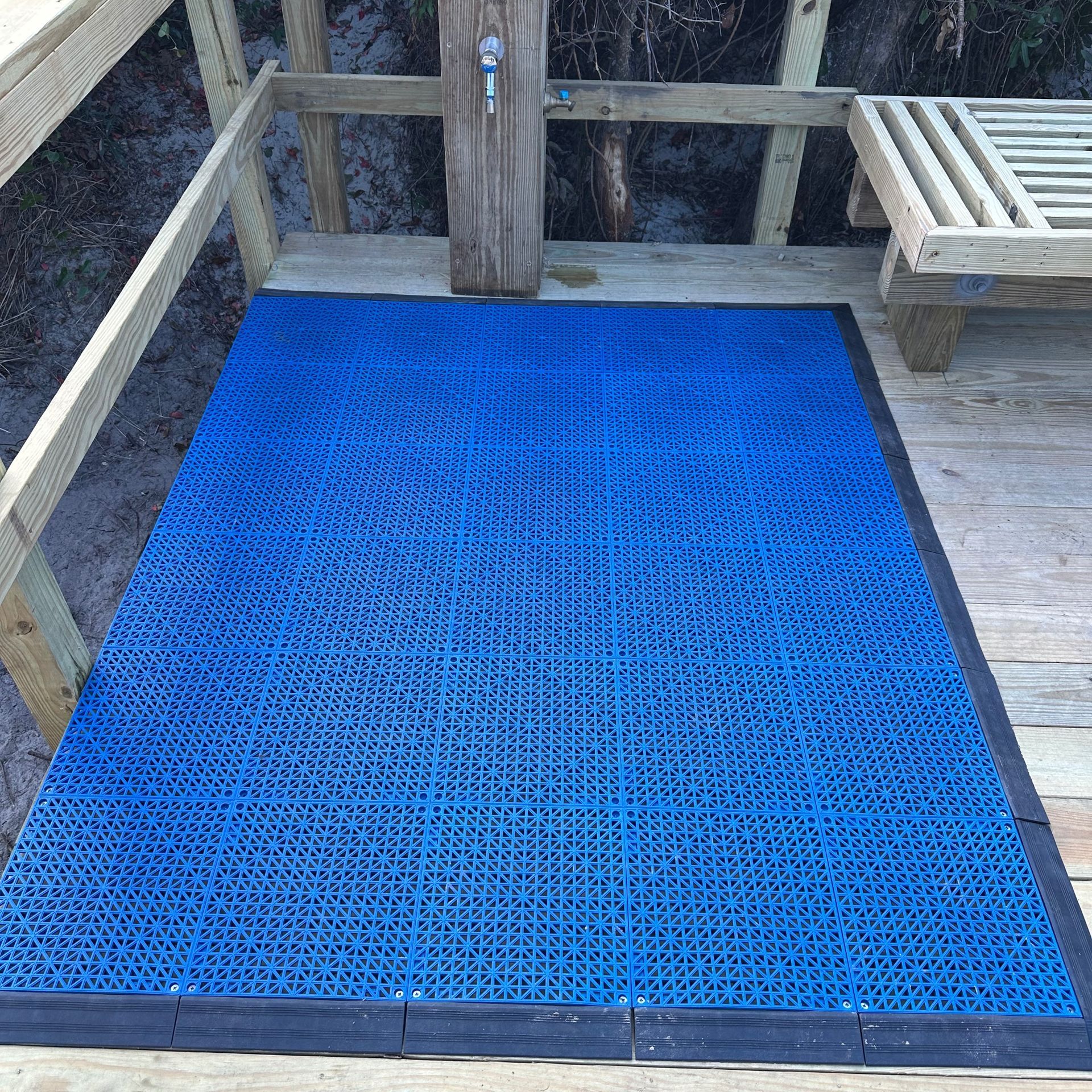 Blue rubber mat on a wooden deck beside a bench and railing.