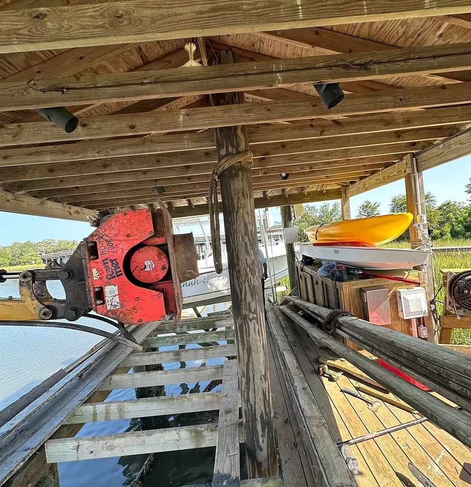 Rustic wooden shelter with stacked kayaks and boats, including a red kayak and yellow canoe.