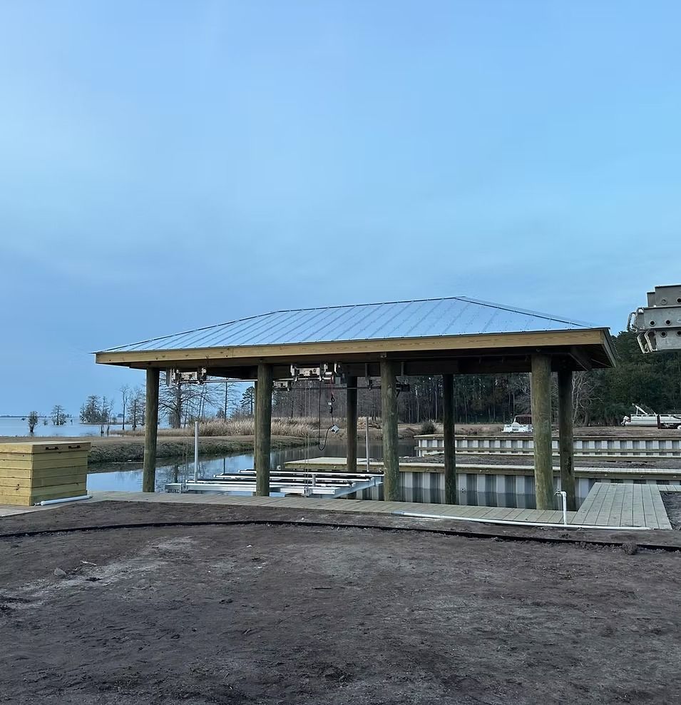 Covered pavilion with a metal roof by the water under a blue sky