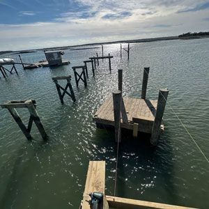 Sunlit marina with several wooden dock frames and platforms on calm, rippling water