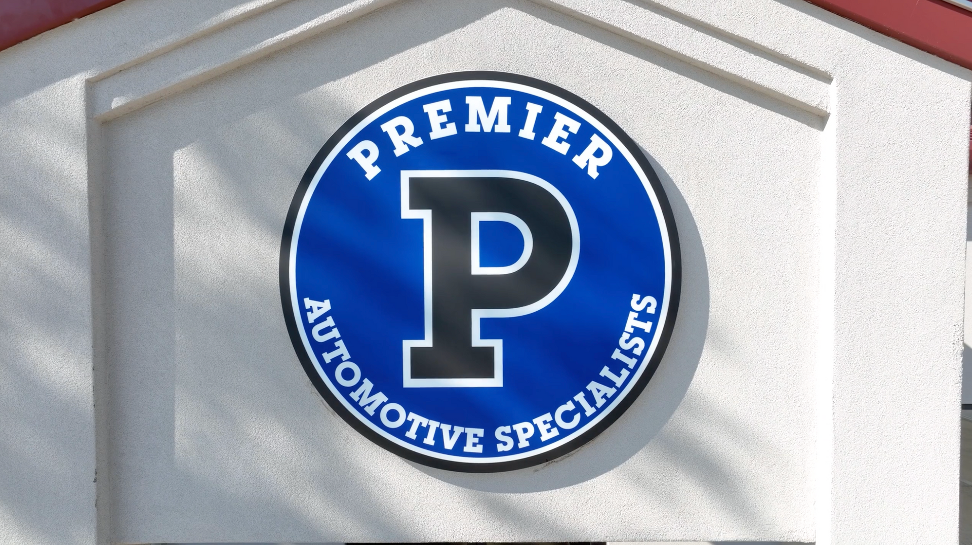 Blue “Premier Automotive Specialists” logo with a white P on a building wall