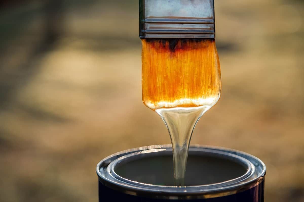 A brush dripping lacquer over an open paint can