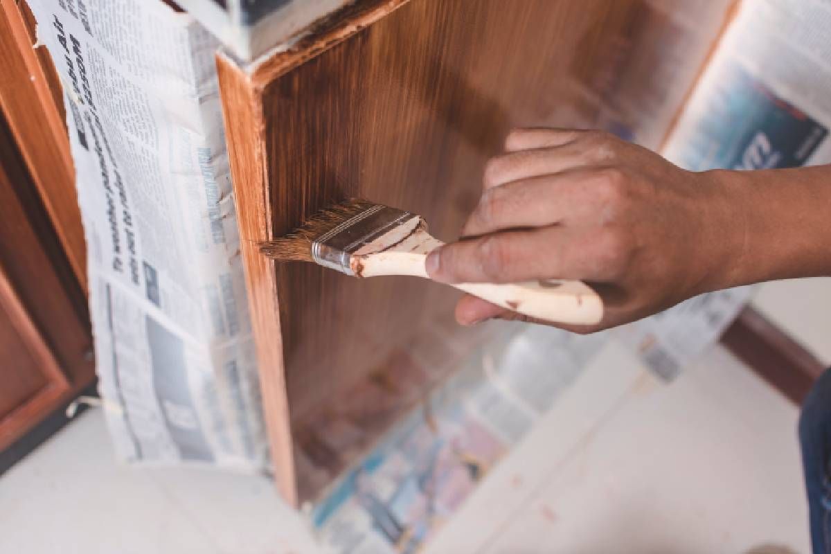 Person applying paint to a cabinet with a brush at Color Store near Des Moines & Waukee, Iowa (IA) & Omaha, Nebraska (NE)