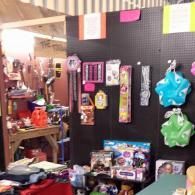 Colorful handmade crafts and toys displayed on shelves in a small shop stall