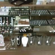 Jewelry store display case with necklaces, bracelets, and rings on shelves and stands