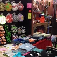 Market stall with colorful plush keychains and folded clothes on display