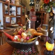 Decorative bowl of fruit and gourds on a wooden table in a cozy shop interior