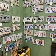 Wall covered with assorted vintage license plates in white, green, blue, and red.