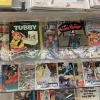 Assorted comic books in plastic sleeves displayed in a shop rack