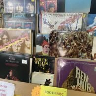 Display of boxed video game and movie covers, including Bruce Willis and Ben-Hur, in a store bin.