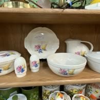 Porcelain floral dinnerware set displayed on a wooden shelf