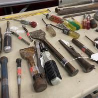 Assorted old hand tools and screwdrivers spread across a workbench