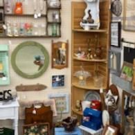 Eclectic shop display with shelves of antiques, mirrors, and small decorative items.