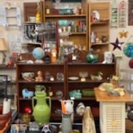Antique shop shelves filled with pottery, globes, and decorative items