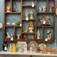 Shelved display of assorted small figurines and decor items on a blue patterned wall