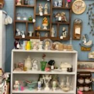 Shelves of assorted handmade ceramic figurines and mugs in a cozy shop display