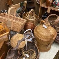 Assorted woven baskets and wooden trays stacked in a market or craft shop display.