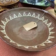 Brown patterned ceramic bowl with a small beige object in the center