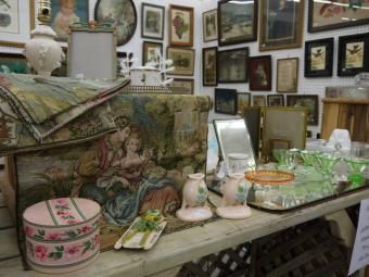 Antique shop display with framed art, mirrors, china, and assorted vintage decorative items