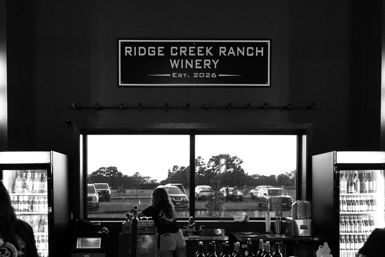 Wine tasting counter at Ridge Creek Ranch Winery, with people silhouetted against a bright window.