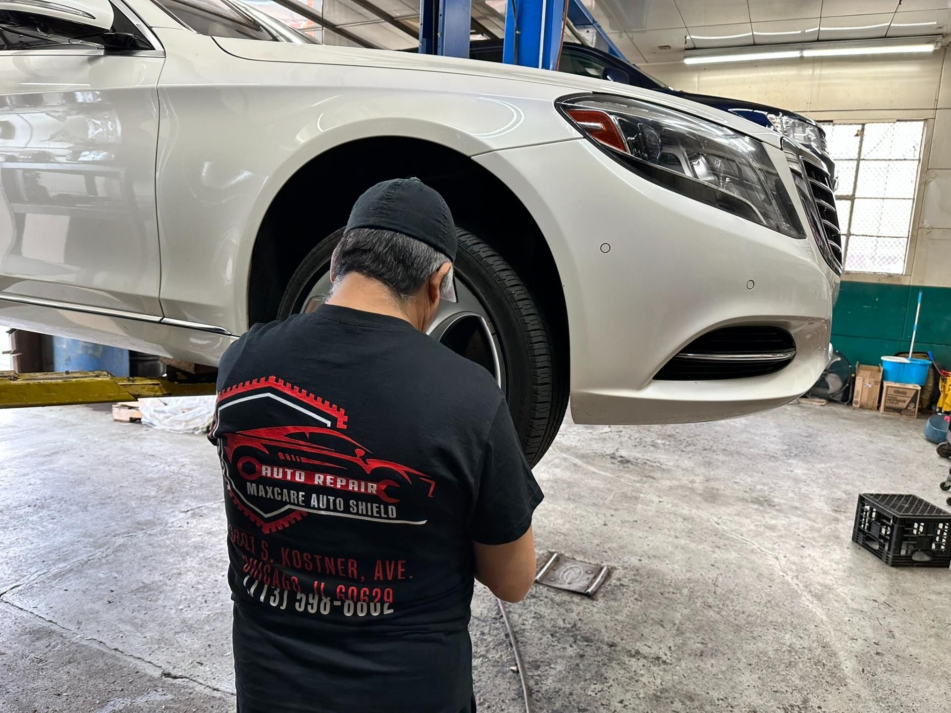Mechanic working under a white car in an auto repair shop