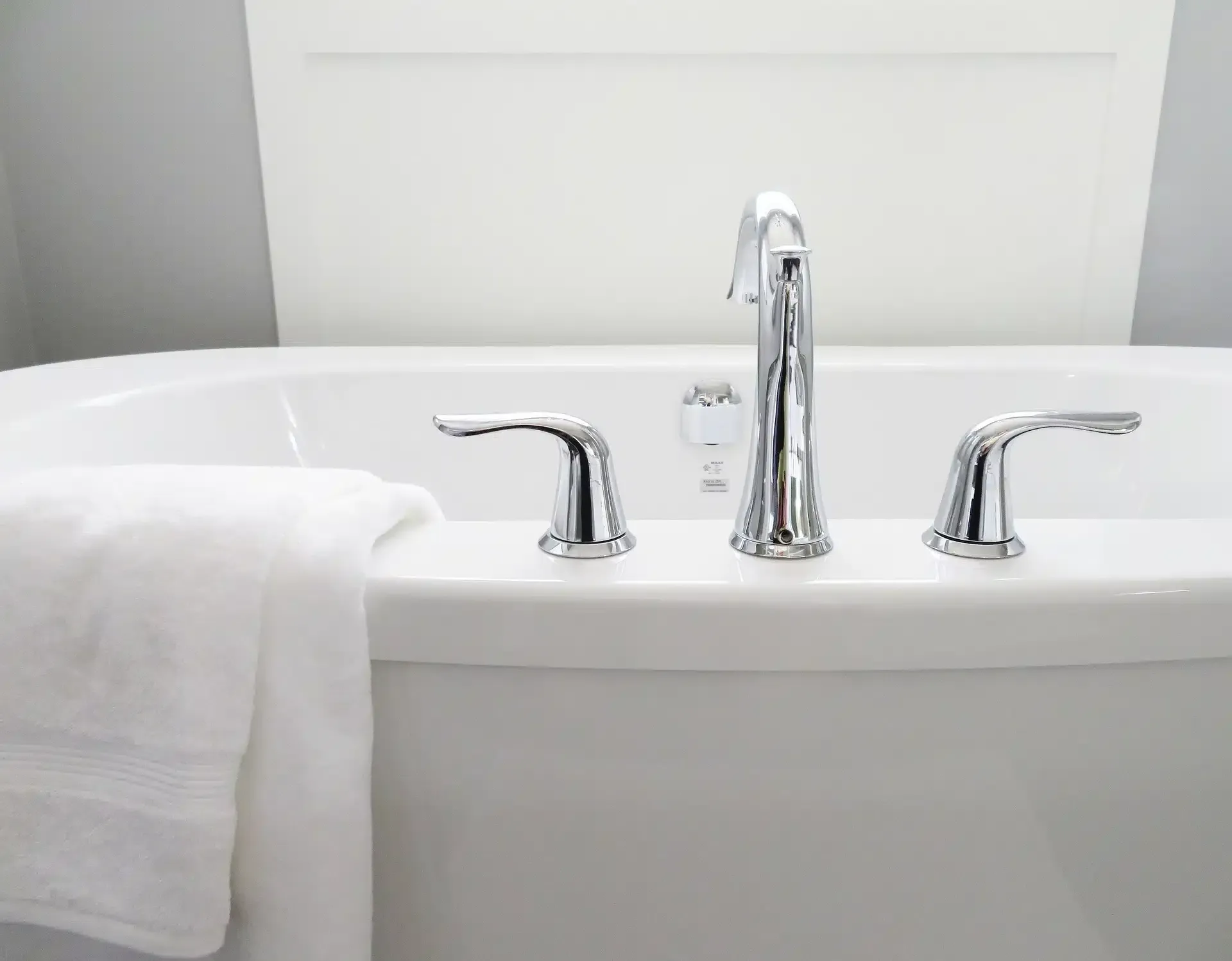 White bathtub with chrome fixtures and a folded white towel.