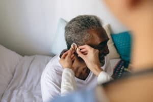 Person adjusting another person's earbud in a cozy indoor setting
