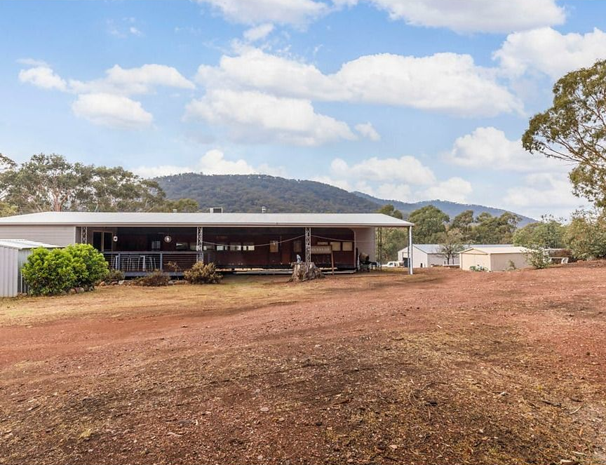Rural Shed with Red Dirt Foreground, Low Hills, and Cloudy Blue Sky — Rivbuild In Uranquinty, NSW