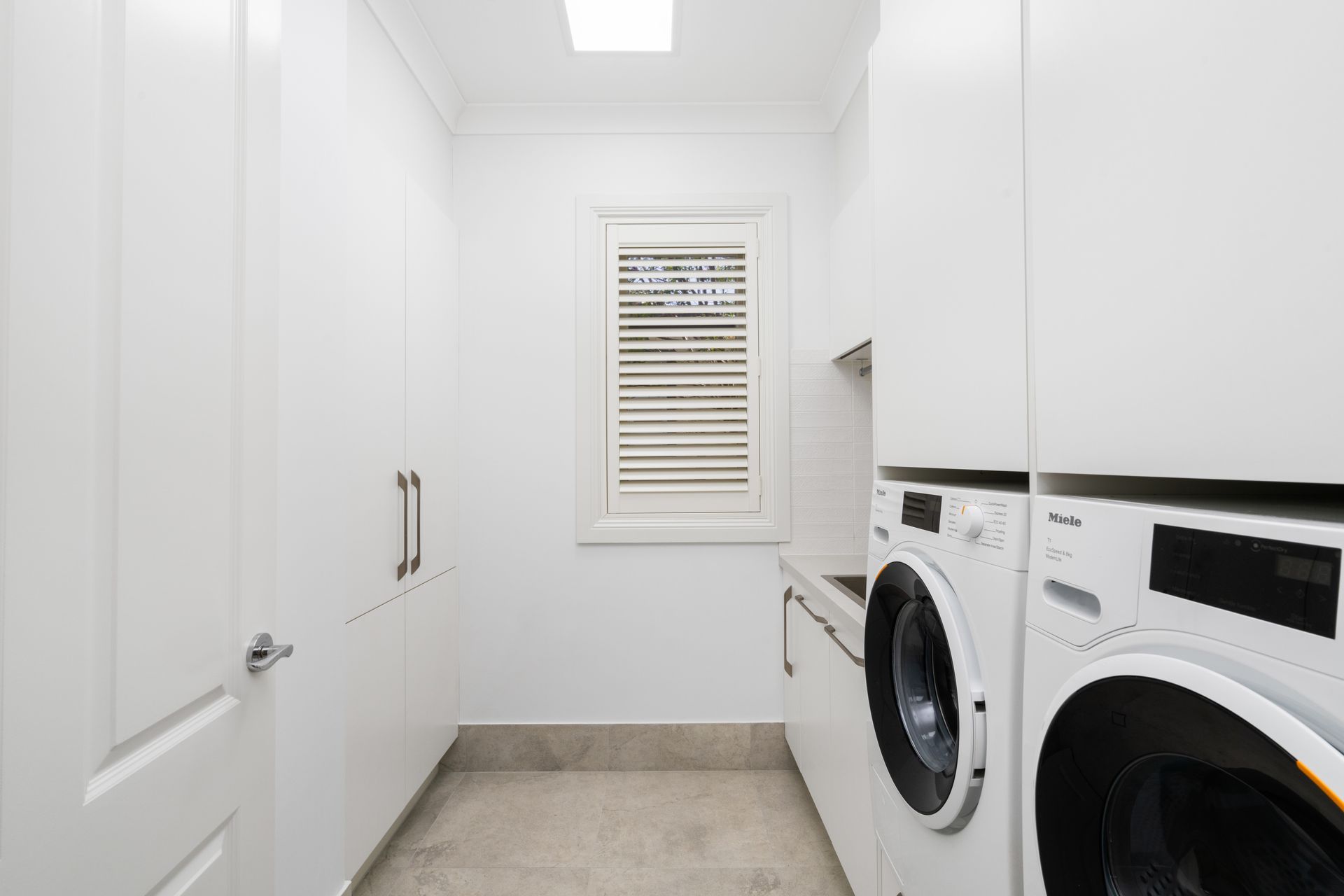 White Laundry Room with Stacked Washer and Dryer, Cabinets — Rivbuild In Uranquinty, NSW