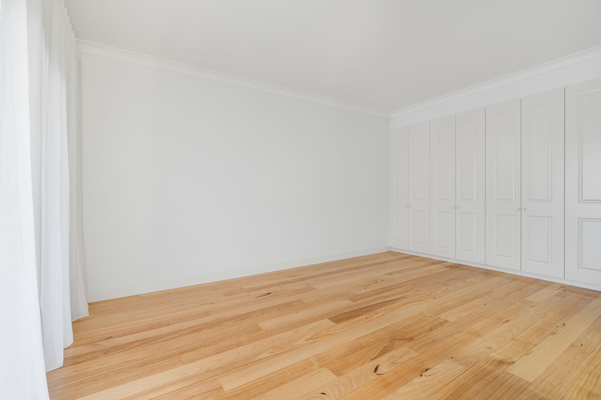 Empty White Room with Light Hardwood Floor and Large Windows — Rivbuild In Uranquinty, NSW