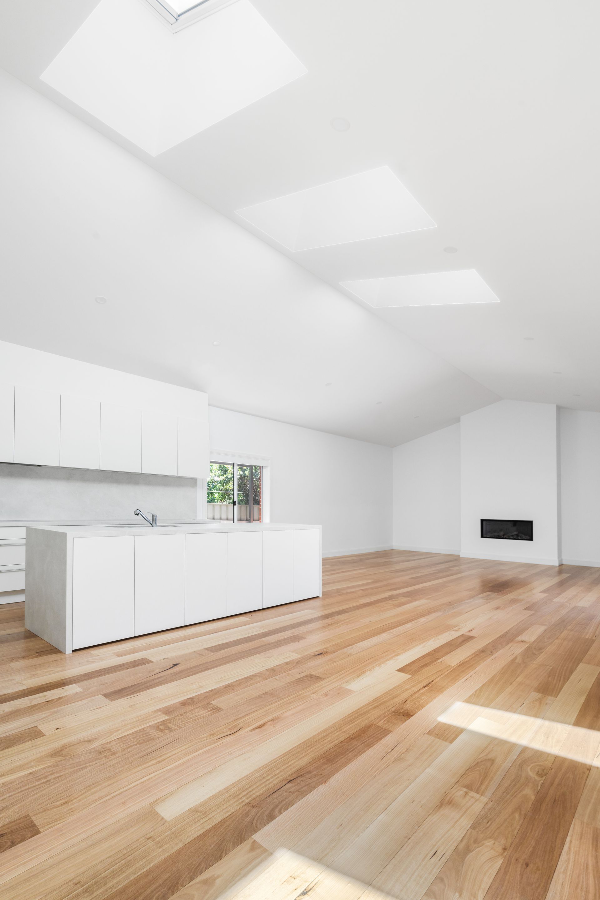 Bright White Modern Kitchen and Living Room with Wood Floors and Skylights — Rivbuild In Uranquinty, NSW