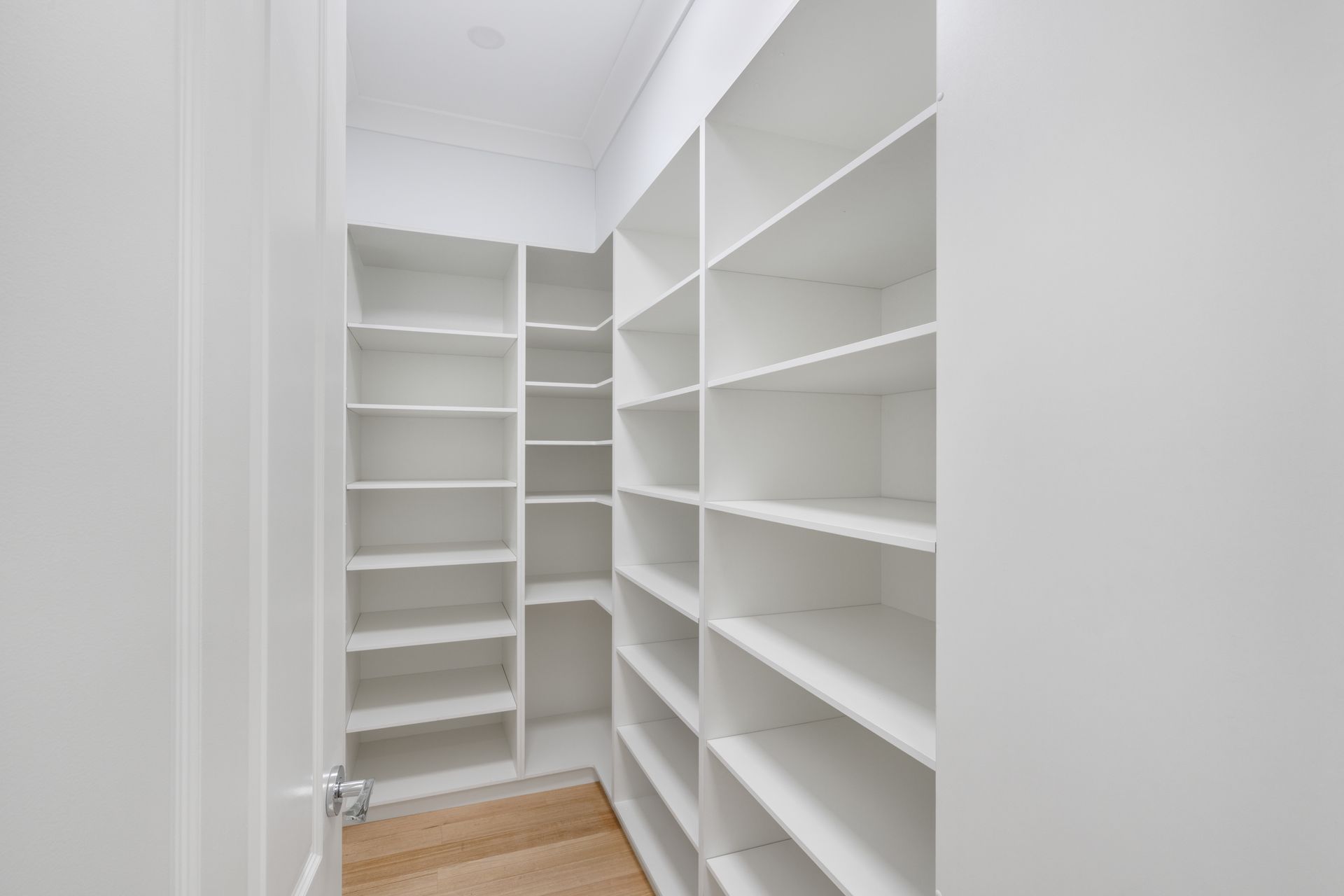 Bright White Walk-In Closet with Built-In Shelves and Wood Flooring — Rivbuild In Uranquinty, NSW