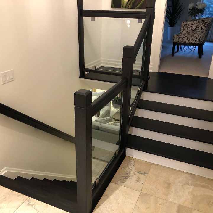 A refinished wooden staircase with a glass railing in a house