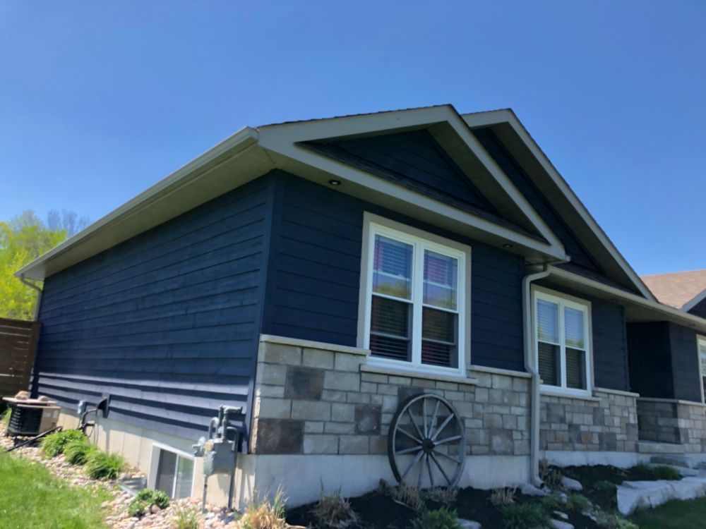 A small blue house with a wagon wheel in front of it, customed painted exterior home.