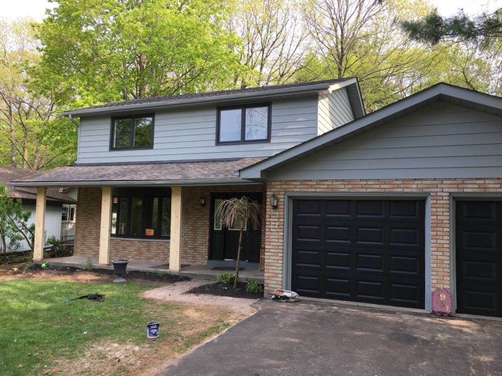 A large house with a black garage door and a porch with customed painted exterior home.