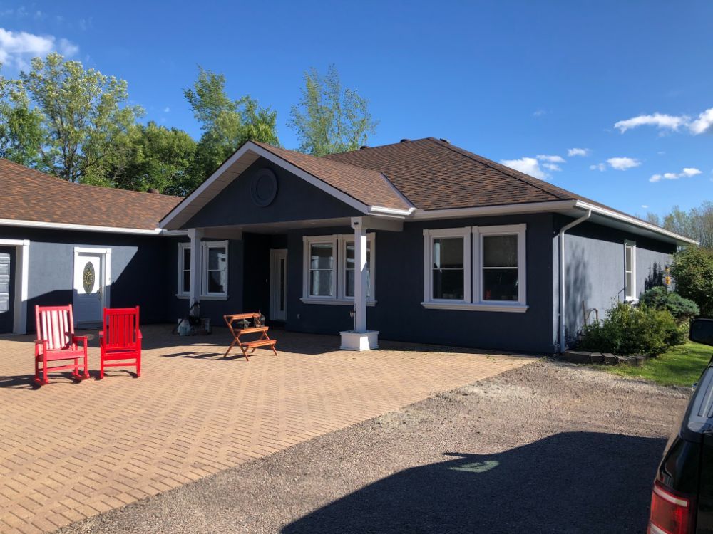 A blue house with red chairs in front of it, customed painted exterior home.