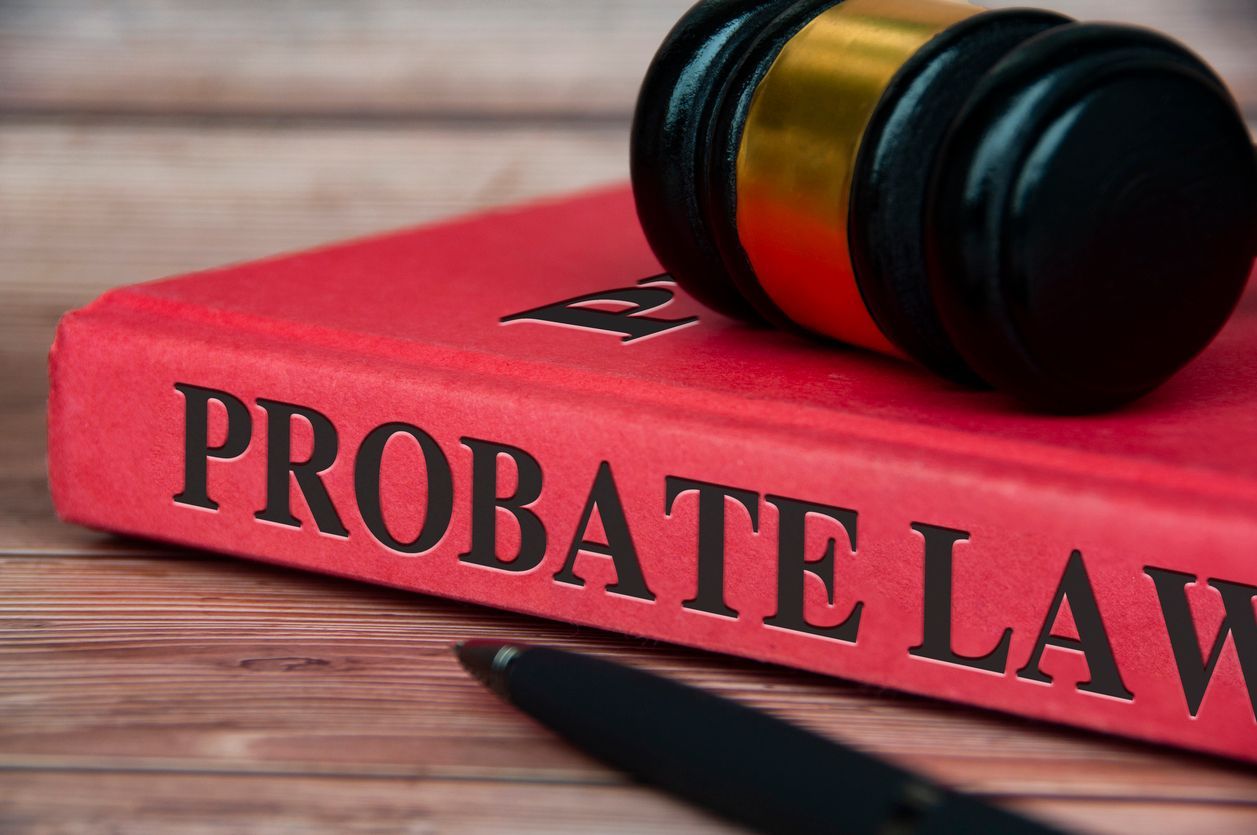 A gavel resting on a red book titled "PROBATE LAW" with a pen in the foreground.