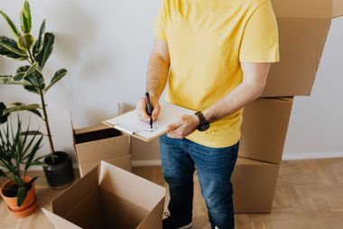 Person packing boxes with a clipboard in a home moving scene