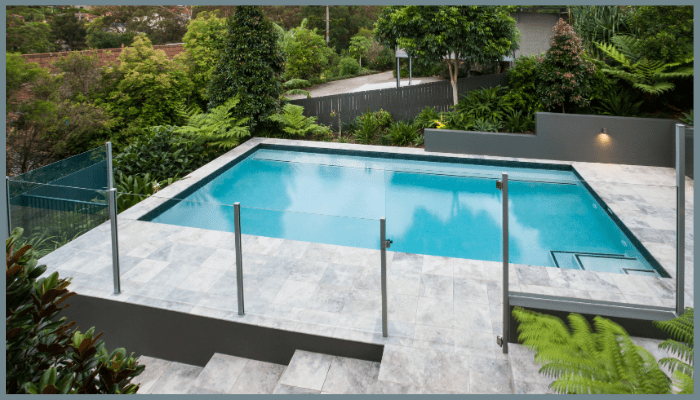 Luxury Canberra infinity pool with frameless glass fencing and lush landscaped garden.