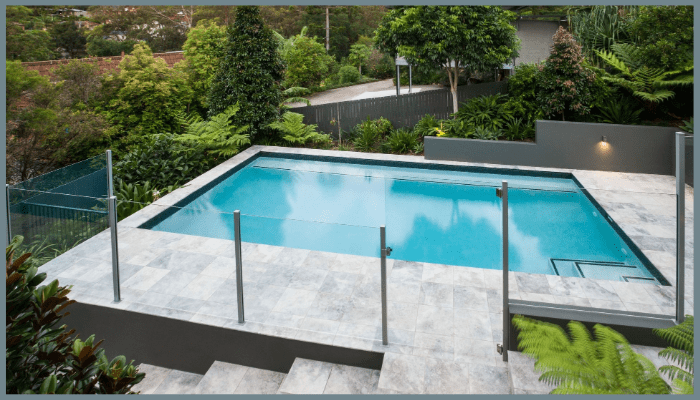 Semi-frameless glass pool fencing with aluminium posts around a modern tiled swimming pool in Canberra.