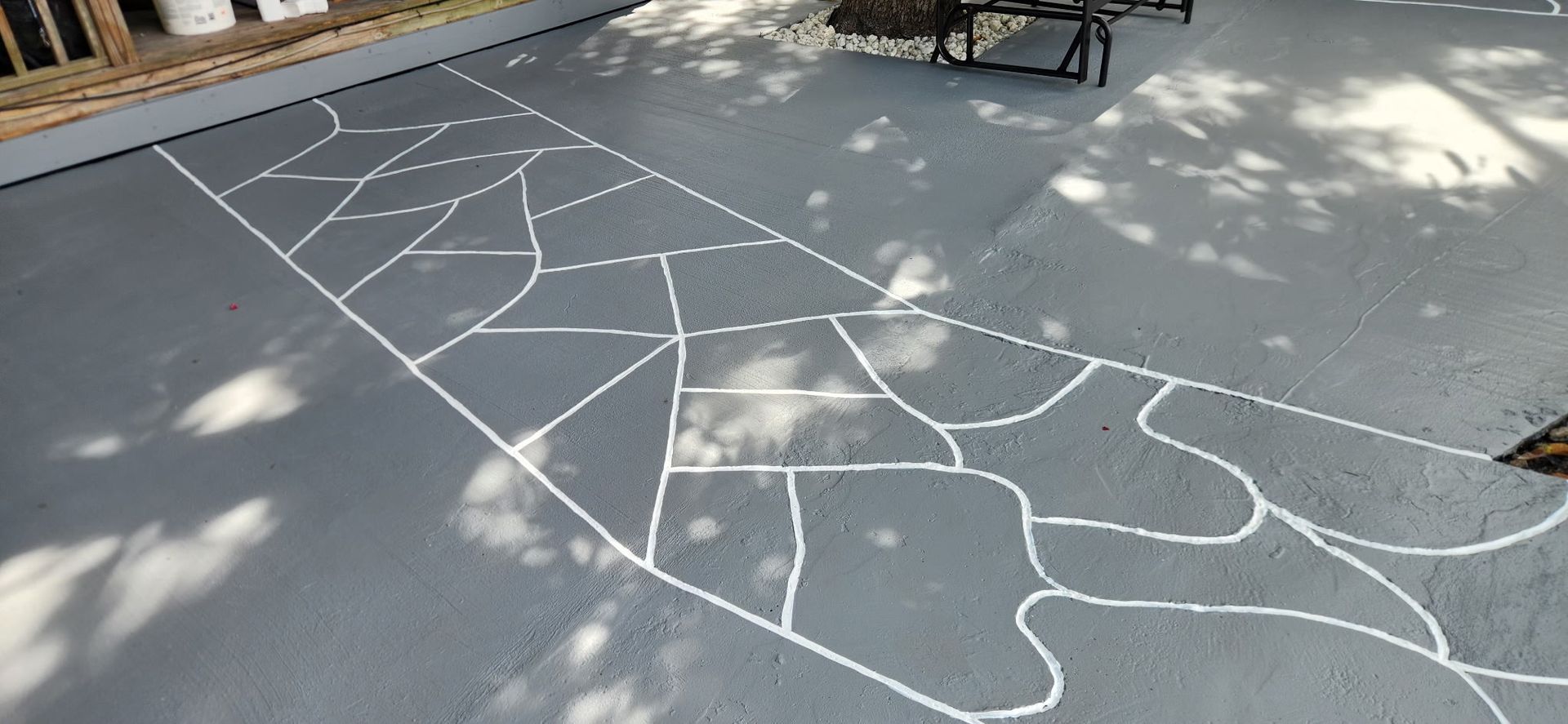 White chalk markings on gray pavement outlining large abstract shapes and path-like segments in an outdoor area