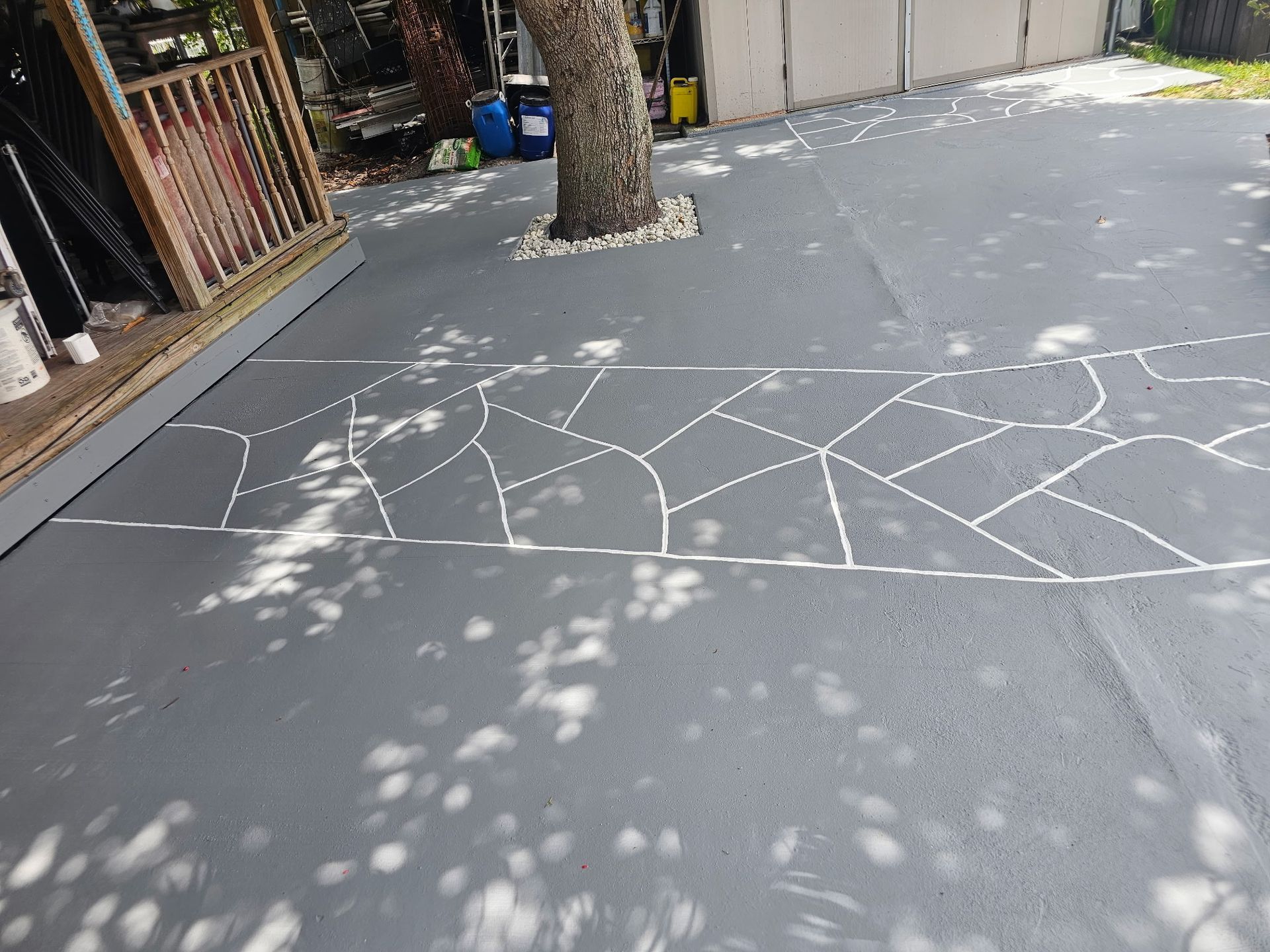 Sidewalk with white chalk geometric lines beside a tree and storefronts on a sunny day