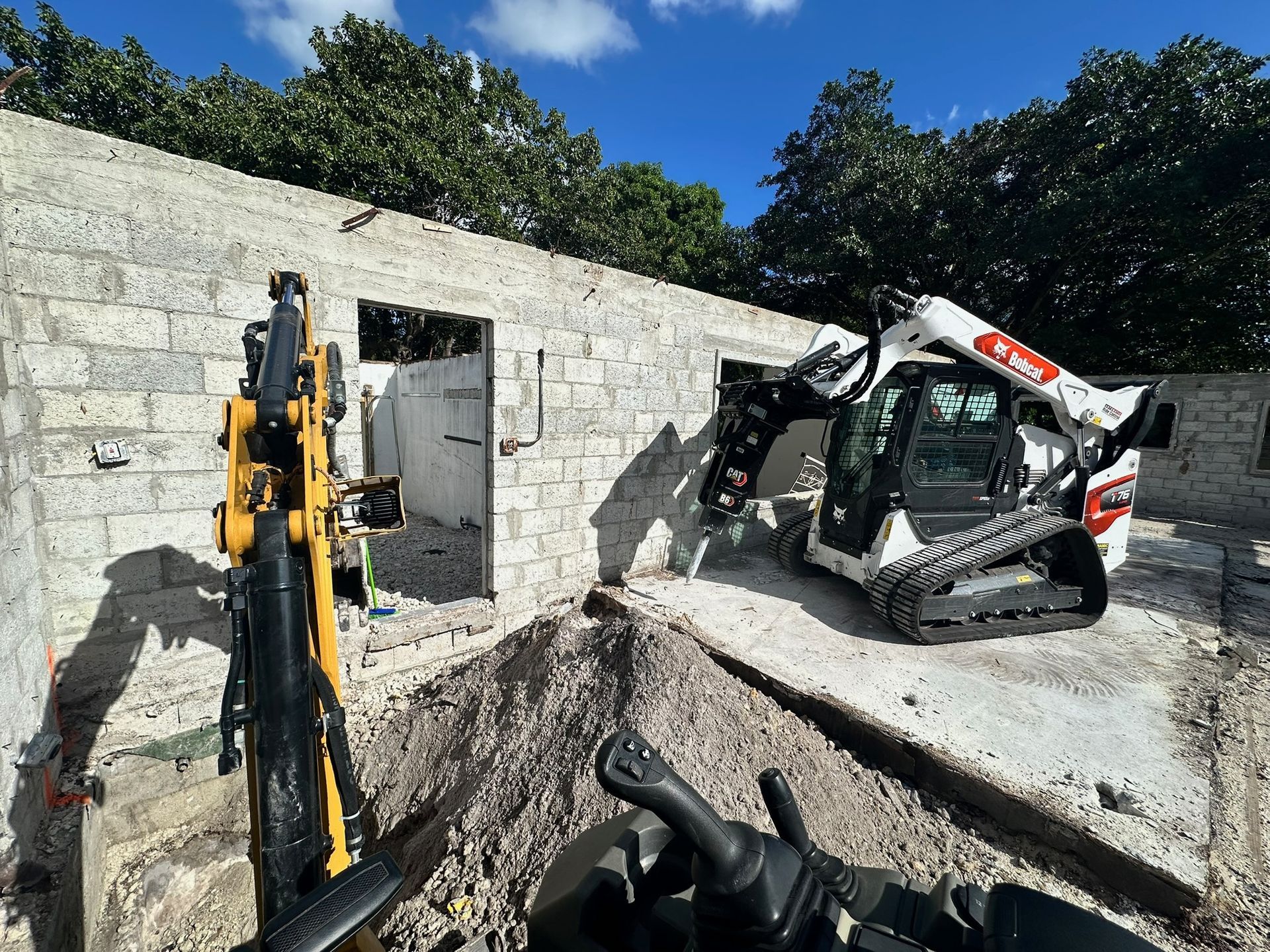 A concrete pump is being used to pour concrete on a construction site with mountains in the background.
