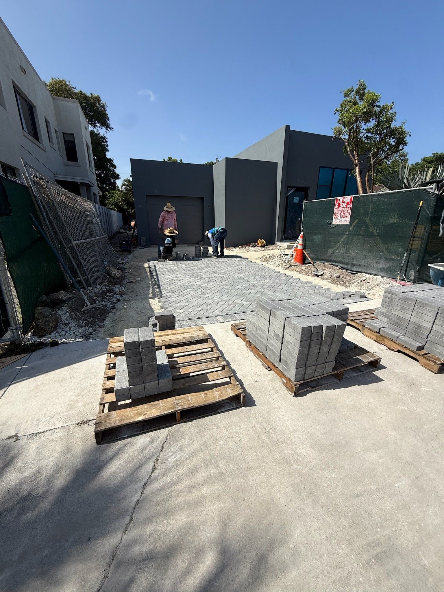 Construction site with concrete forms and a worker near a gray building on a sunny day