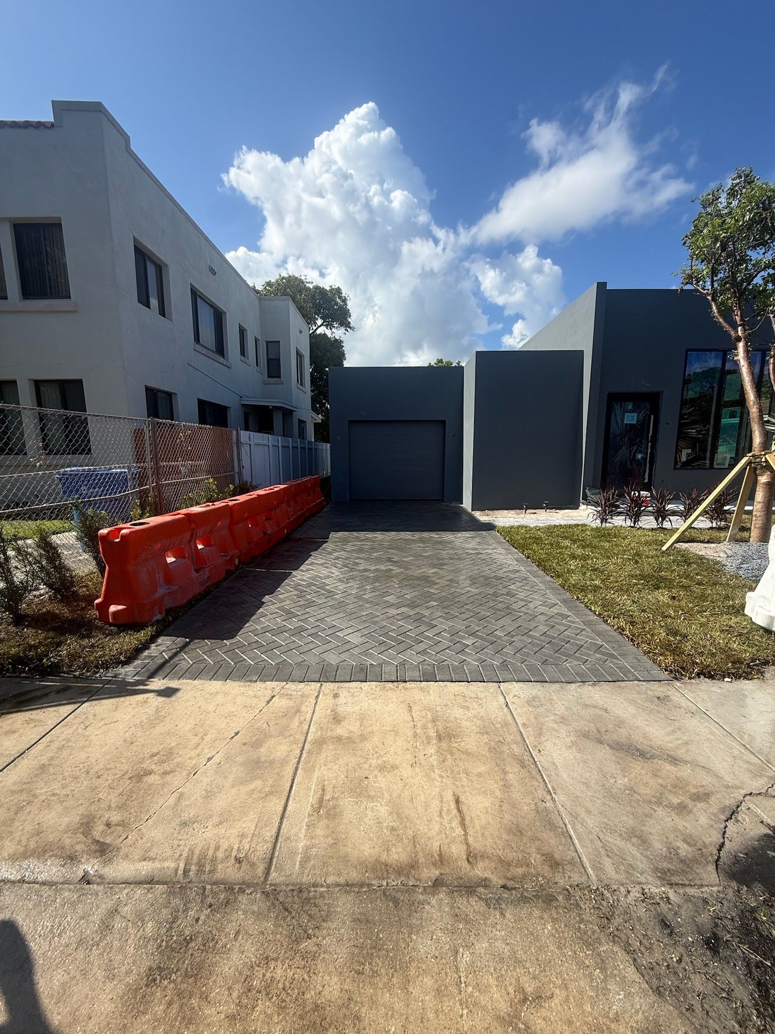 Modern house exterior with gravel driveway, orange construction barrier, and blue sky